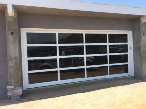 White aluminum full-view garage door with clear glass panels on stucco home