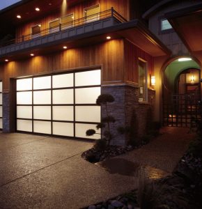 White aluminum full-view garage door with frosted glass panels on luxury stone home at night