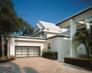 White aluminum full-view garage door with frosted glass on white contemporary home with palms