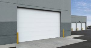 White commercial sectional steel garage door on grey industrial building
