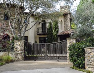 Ornate wrought iron driveway gate at luxury estate with stone pillars