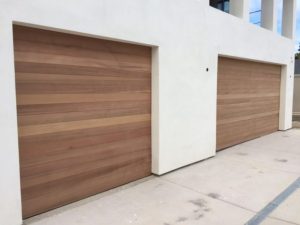 Honey oak flush horizontal wood garage door on white modern home