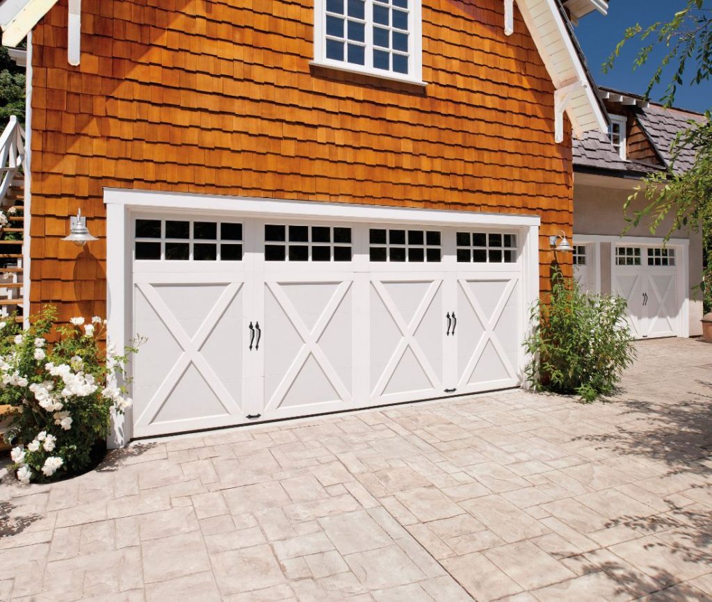 White MCS-30 Coachman steel carriage-style garage door with X-brace panels and upper windows on cedar shingle home