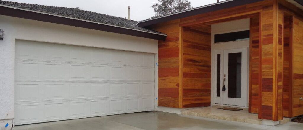 Before: original white raised-panel garage door on wood-clad modern home